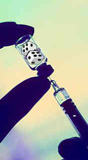 fingers holding bottle and syringe that is being filled - in the bottle is a pair of dice